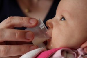 Newborn being fed by cup 300x200